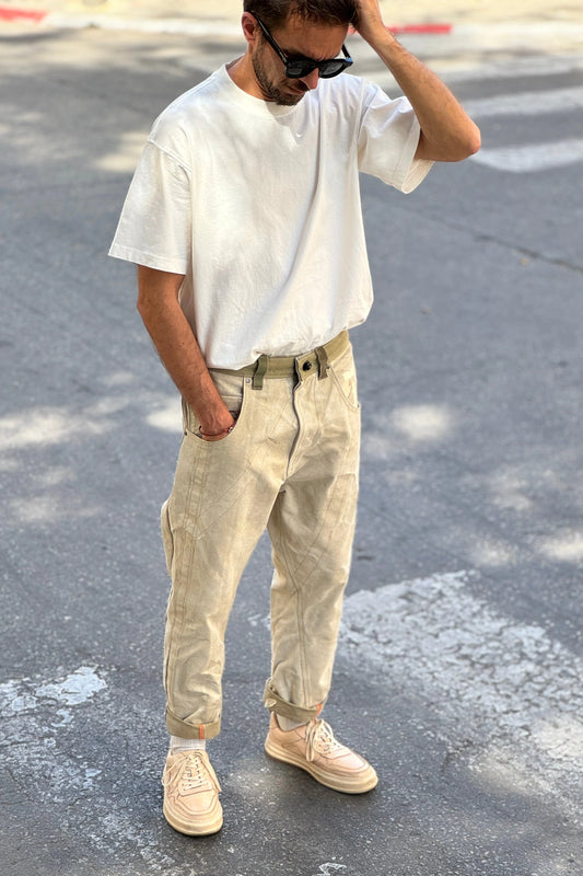 Man wearing a white t-shirt and beige pants standing on a street.