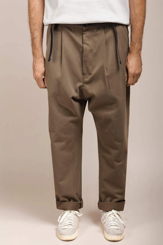 An eye-level view of a model wearing khaki pants and white sneakers