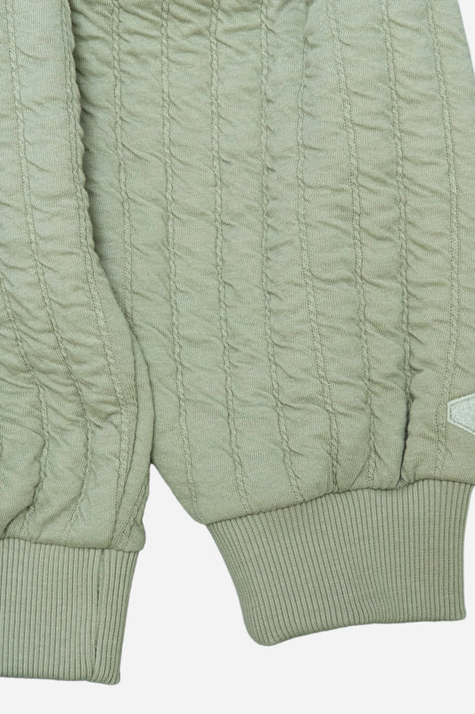 Close-up of light green knit hoodie with textured vertical stripes and ribbed cuffs