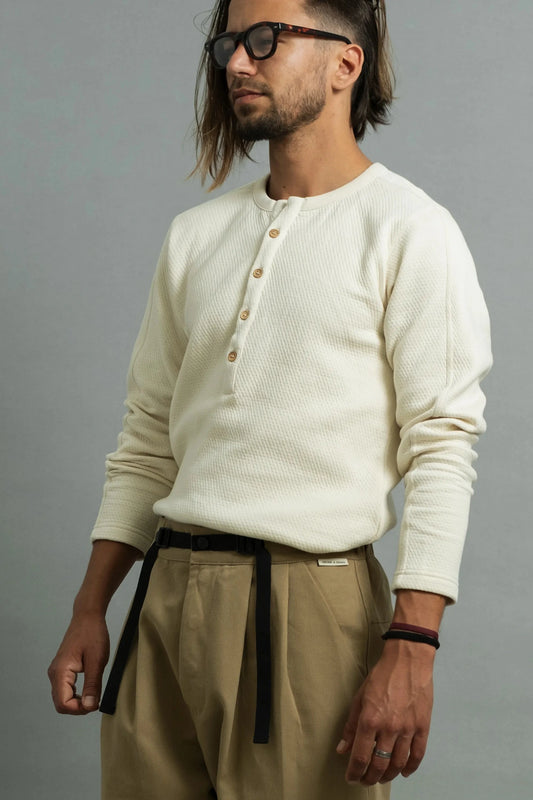 Man wearing a bone henley, dark tortoise shell glasses, and khaki pants