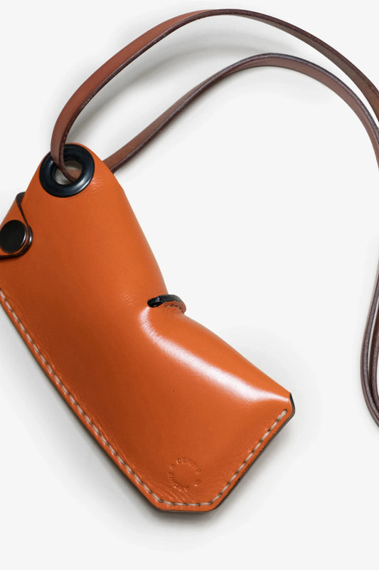 Orange leather glasses case with contrast stitching and a black snap closure, featuring a brown leather strap looped through a reinforced eyelet for easy carrying.