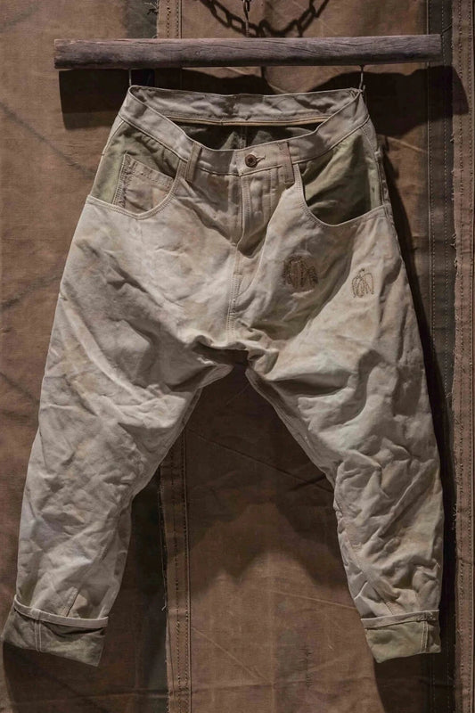 Front view of neutral-colored army pants hanging against a brown backdrop