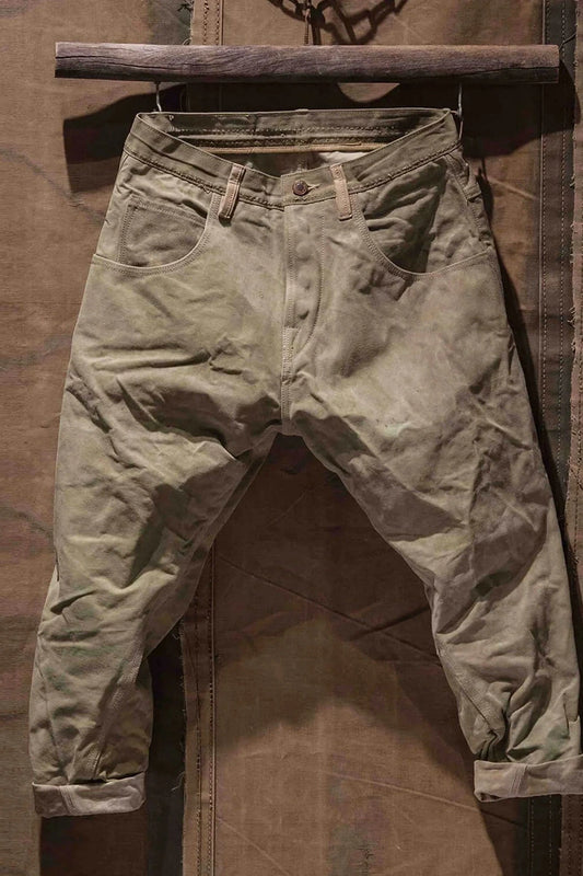 Full view of army pants hanging on a wooden bar