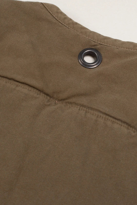 Close-up of a green quilted vest with a metal grommet