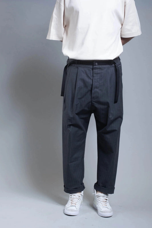 A man wearing navy herringbone pants and a light-colored tee