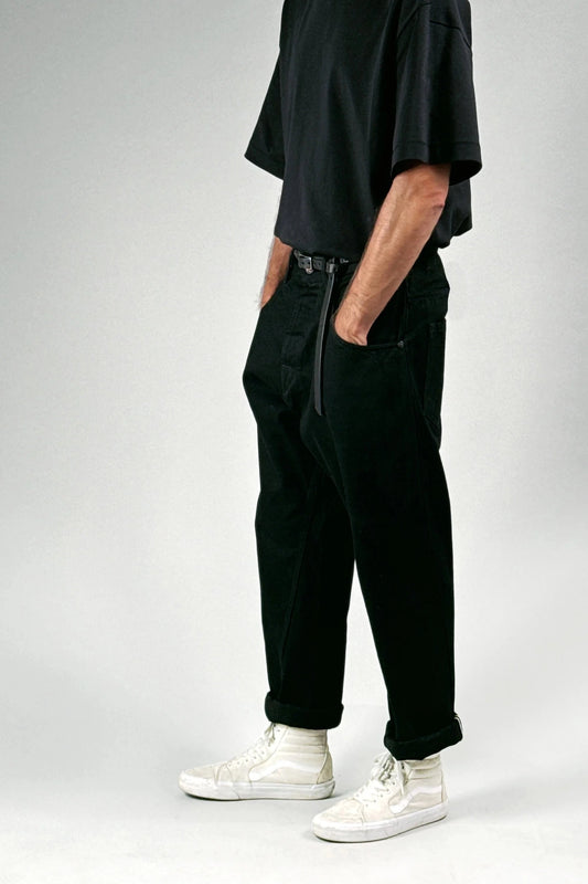 A person wearing black denim pants, t-shirt, and white high-top sneakers