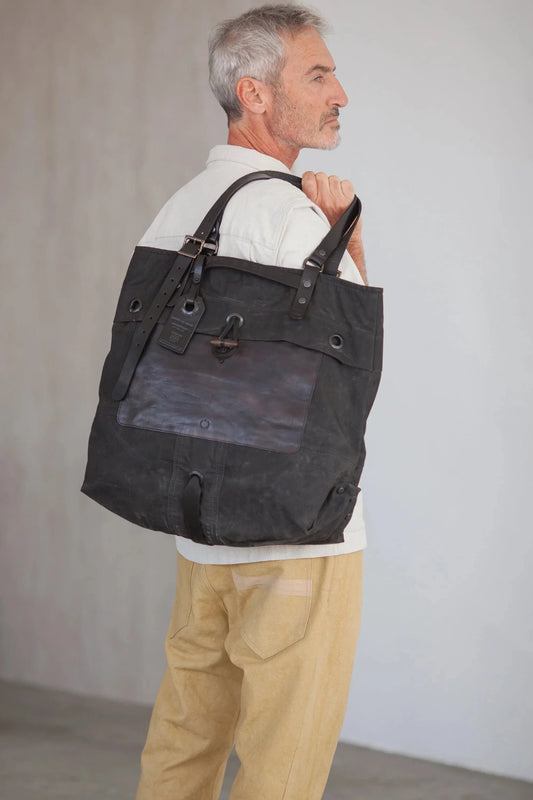 Profile view of a man carrying a black tote bag over his shoulder
