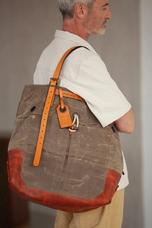 Side view of a man wearing a tote bag with an orange leather bottom and straps