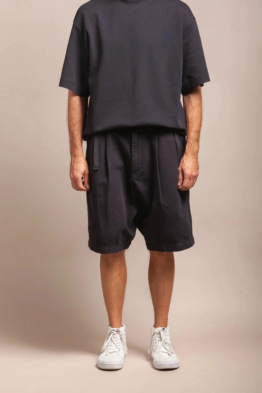 A model wearing black shorts and a black t-shirt with white shoes