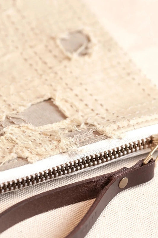 Close-up of a rustic beige pouch with distressed fabric detail and a leather strap