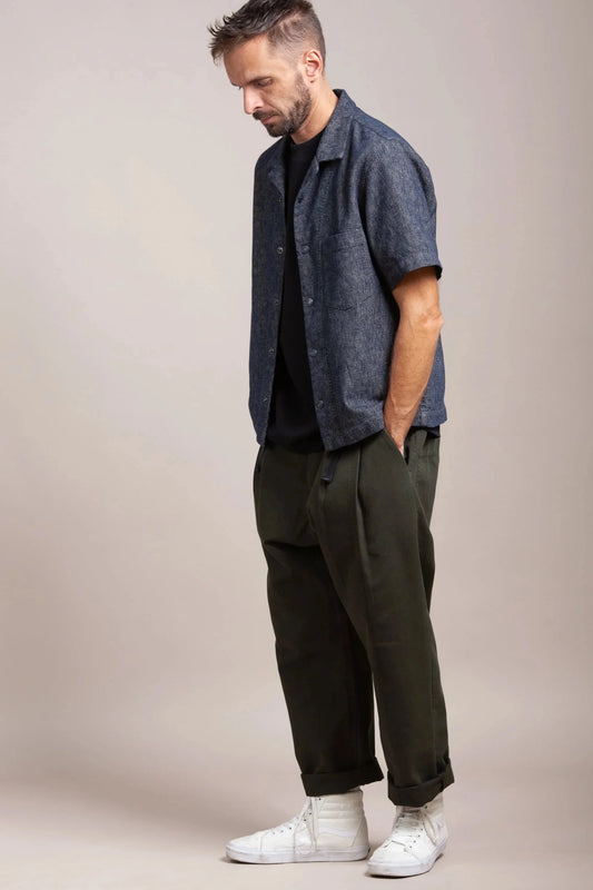 Man wearing a gray bowling shirt, dark pants, and high-top sneakers