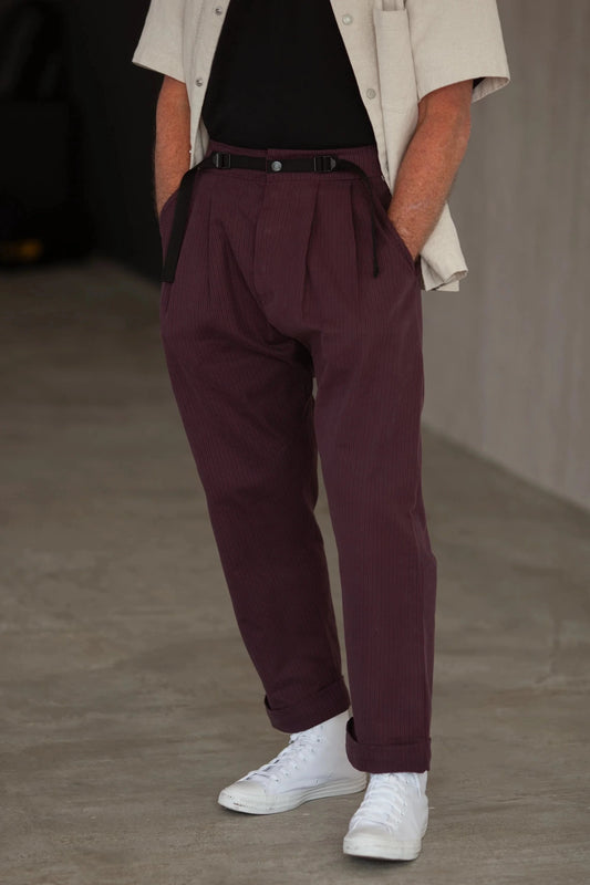 Man wearing burgundy herringbone patton pants, black t-shirt, and white sneakers