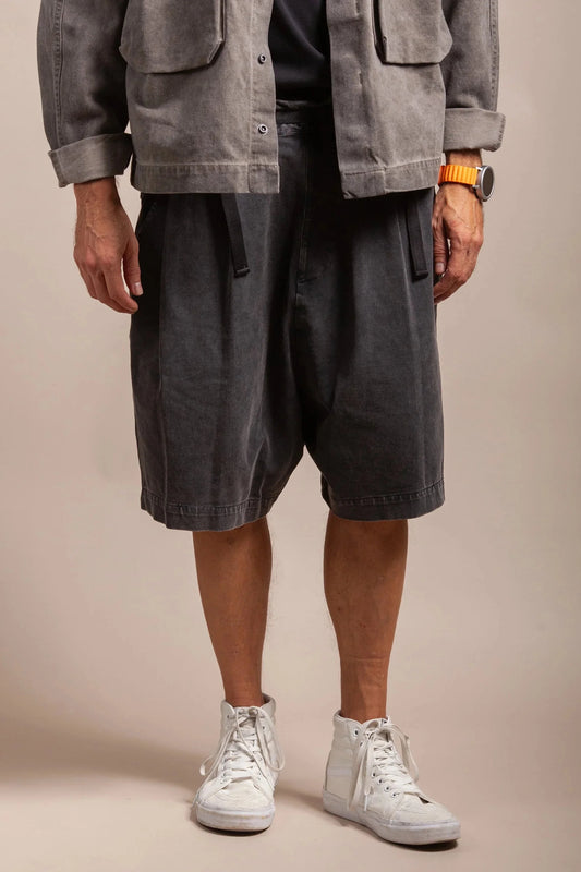 Man wearing washed black shorts, grey jacket, high-top sneakers, and an orange watch