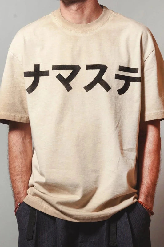 Man wearing a sand fade NAMASTE t-shirt with hands in pockets