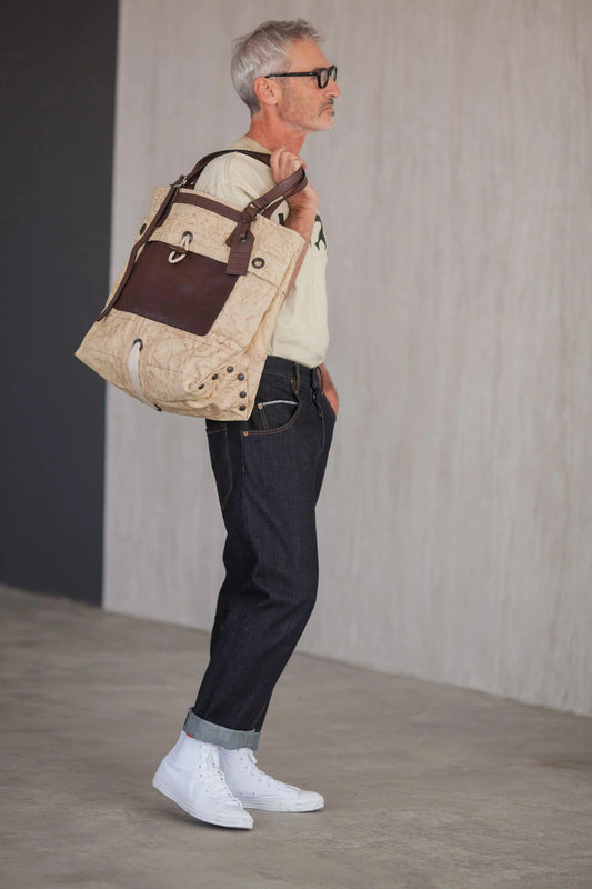 Side view of a man carrying a light-colored Benzin tote bag