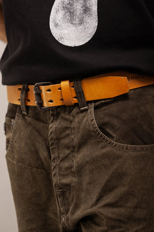 Close-up of a person wearing a tan leather belt with dark brown pants