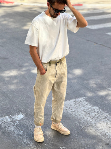 Man wearing a white t-shirt and beige pants standing on a street.