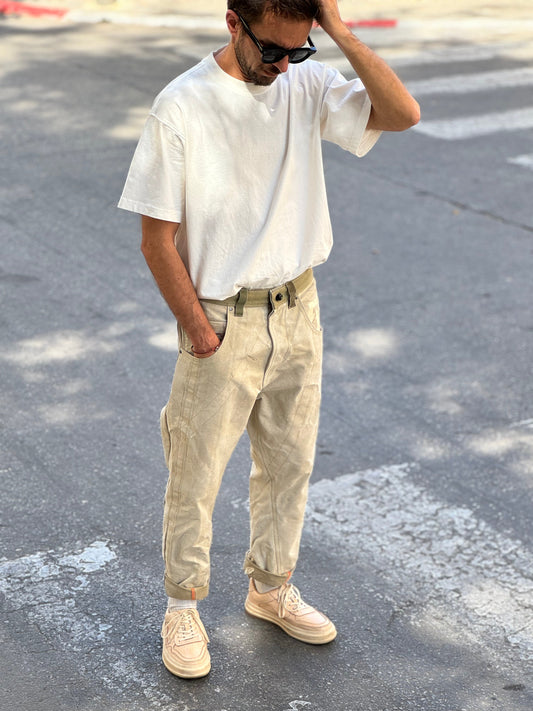 Man wearing a white t-shirt and beige pants standing on a street.