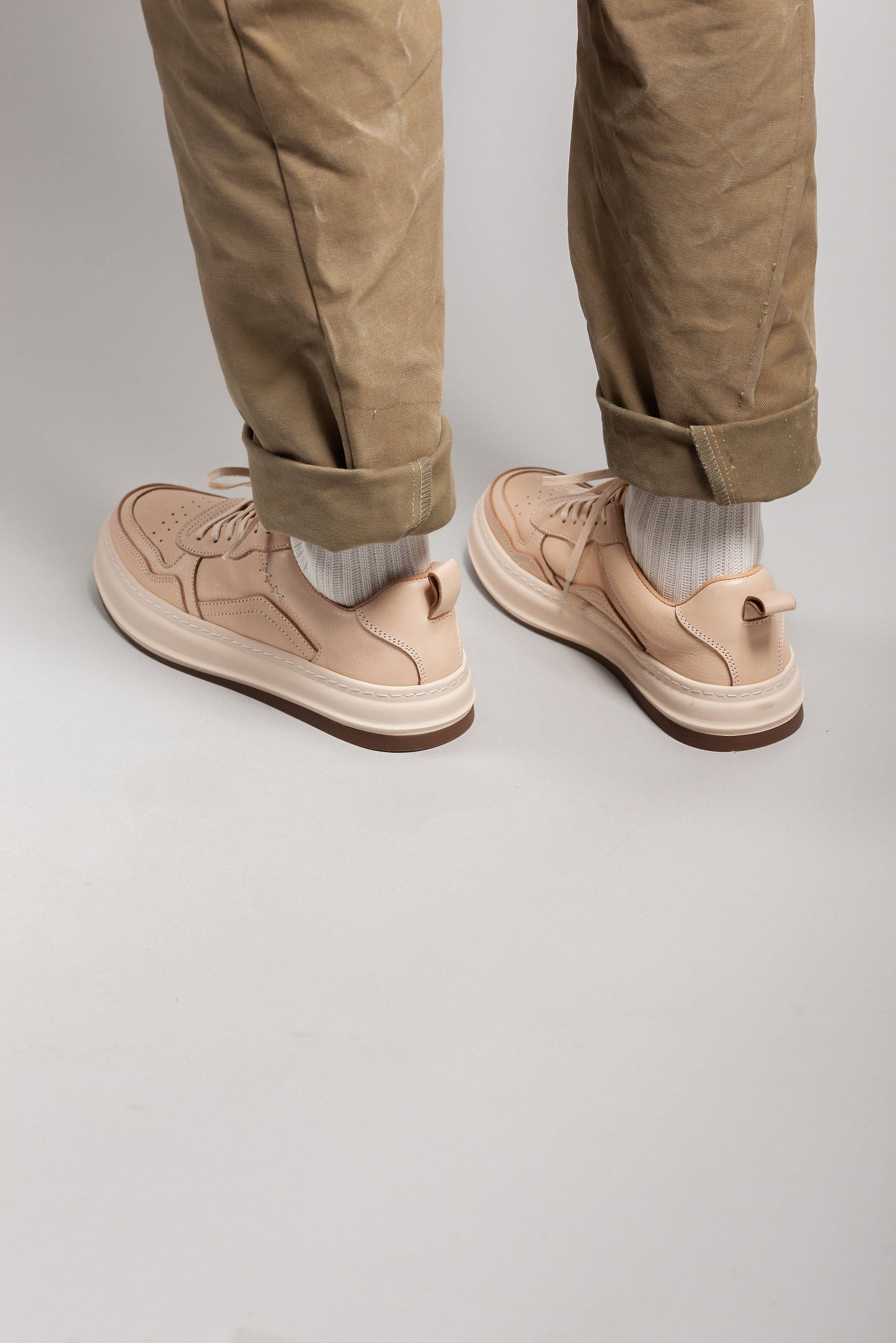 A low angle shot of khaki pants and creamy white leather sneakers