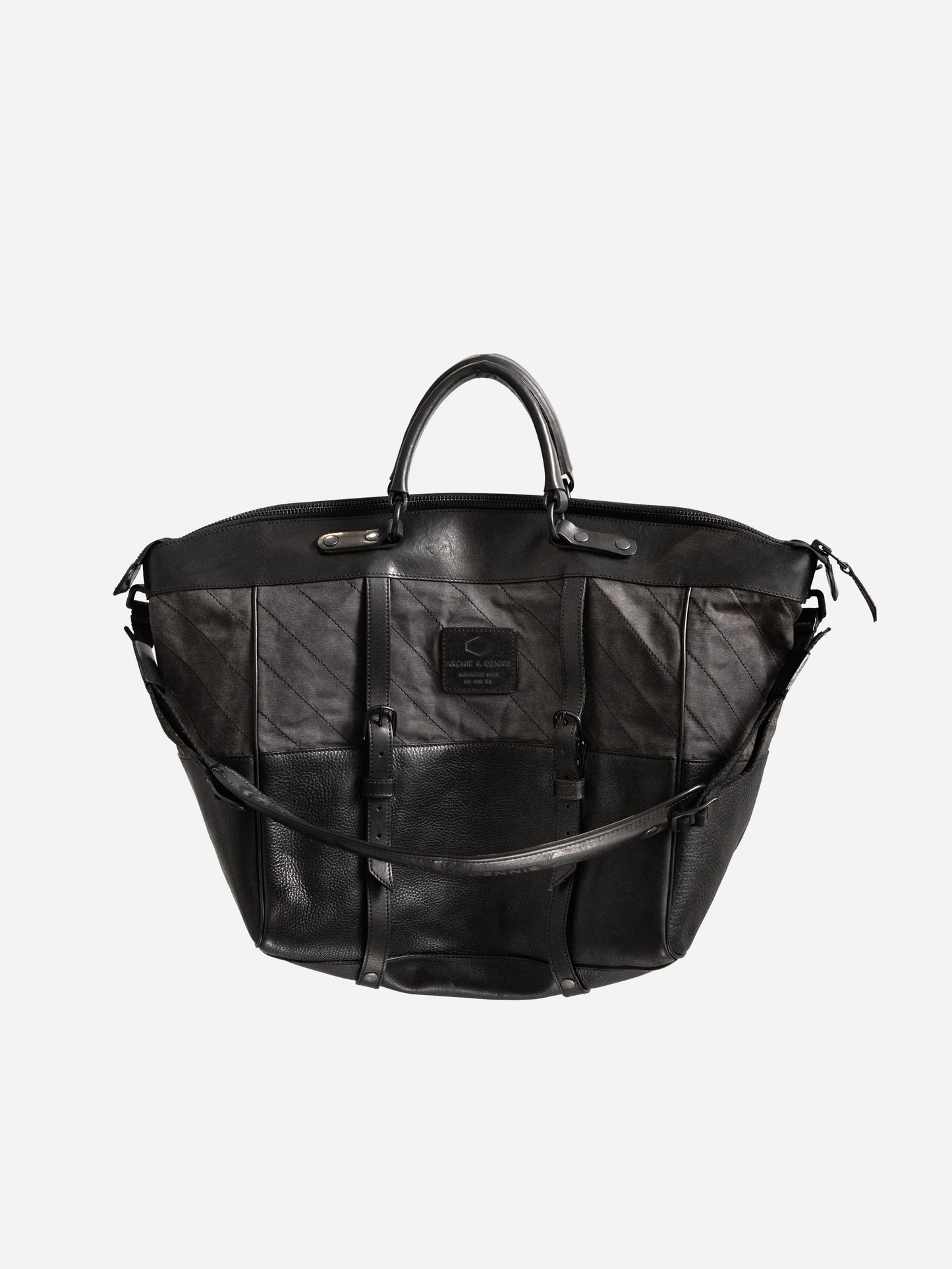 Black leather weekend bag with dual handles and adjustable shoulder strap, featuring a stitched patch detail and durable, structured design.