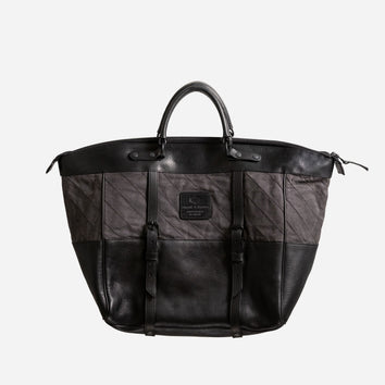 Black and dark gray handcrafted weekend bag with leather accents, dual buckle straps, and a sturdy handle, featuring a minimalist design ideal for utility-inspired menswear.