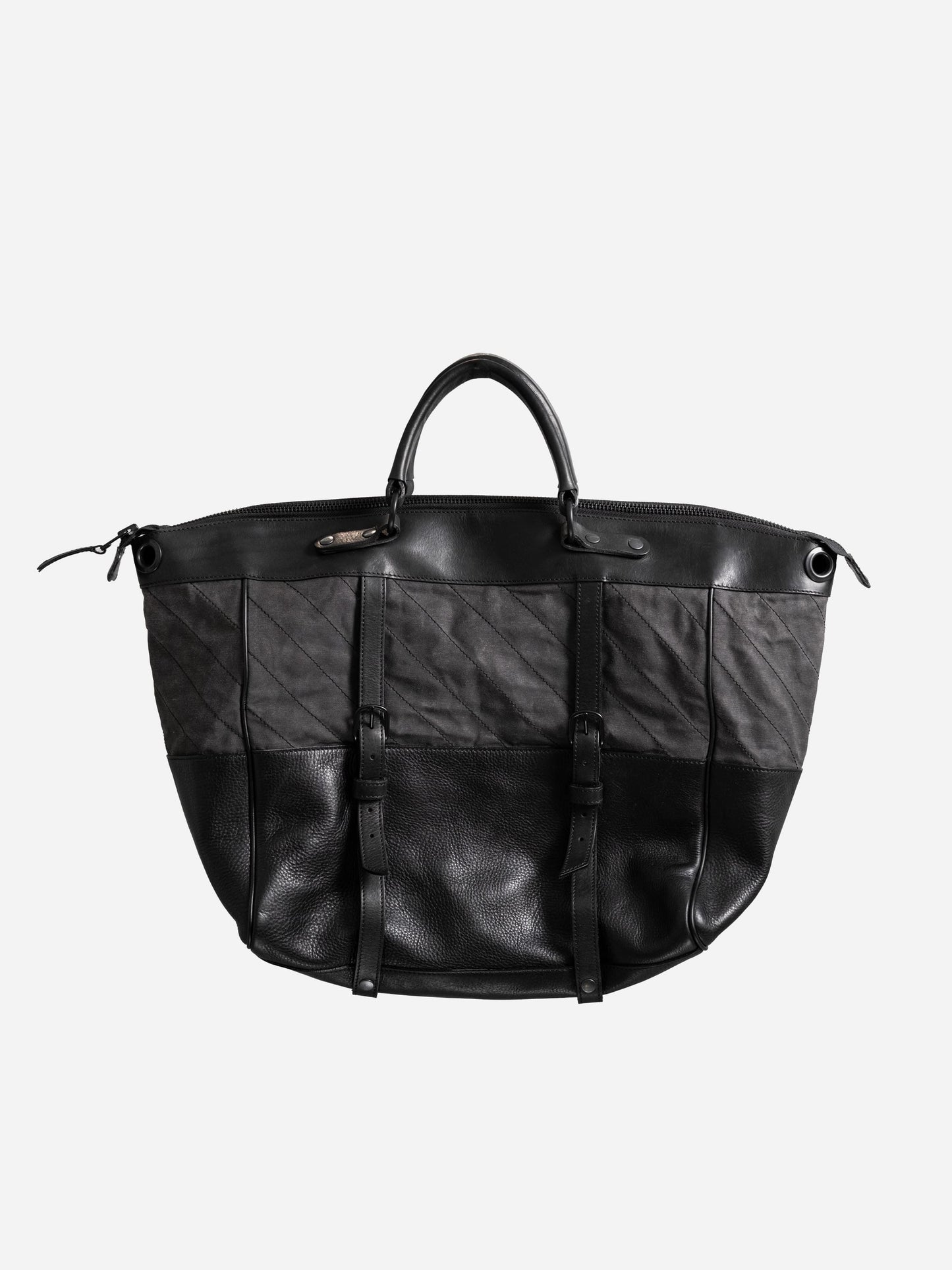 Black and dark gray handcrafted weekend bag with leather handles and buckle straps, combining utility style and vintage-inspired materials for a unique men's accessory.
