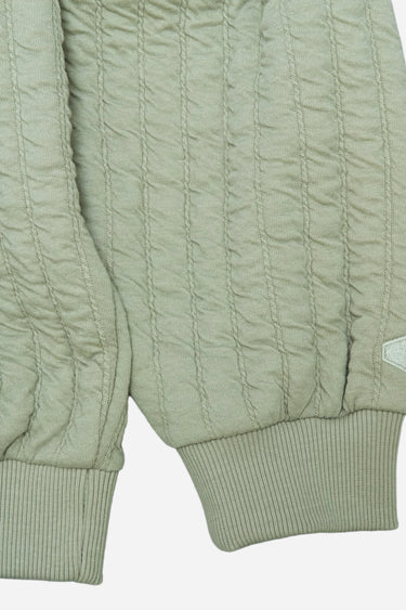 Close-up of light green knit hoodie with textured vertical stripes and ribbed cuffs