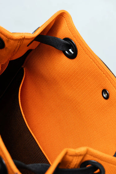 Close-up view into the orange backpack with black drawstring and grommets