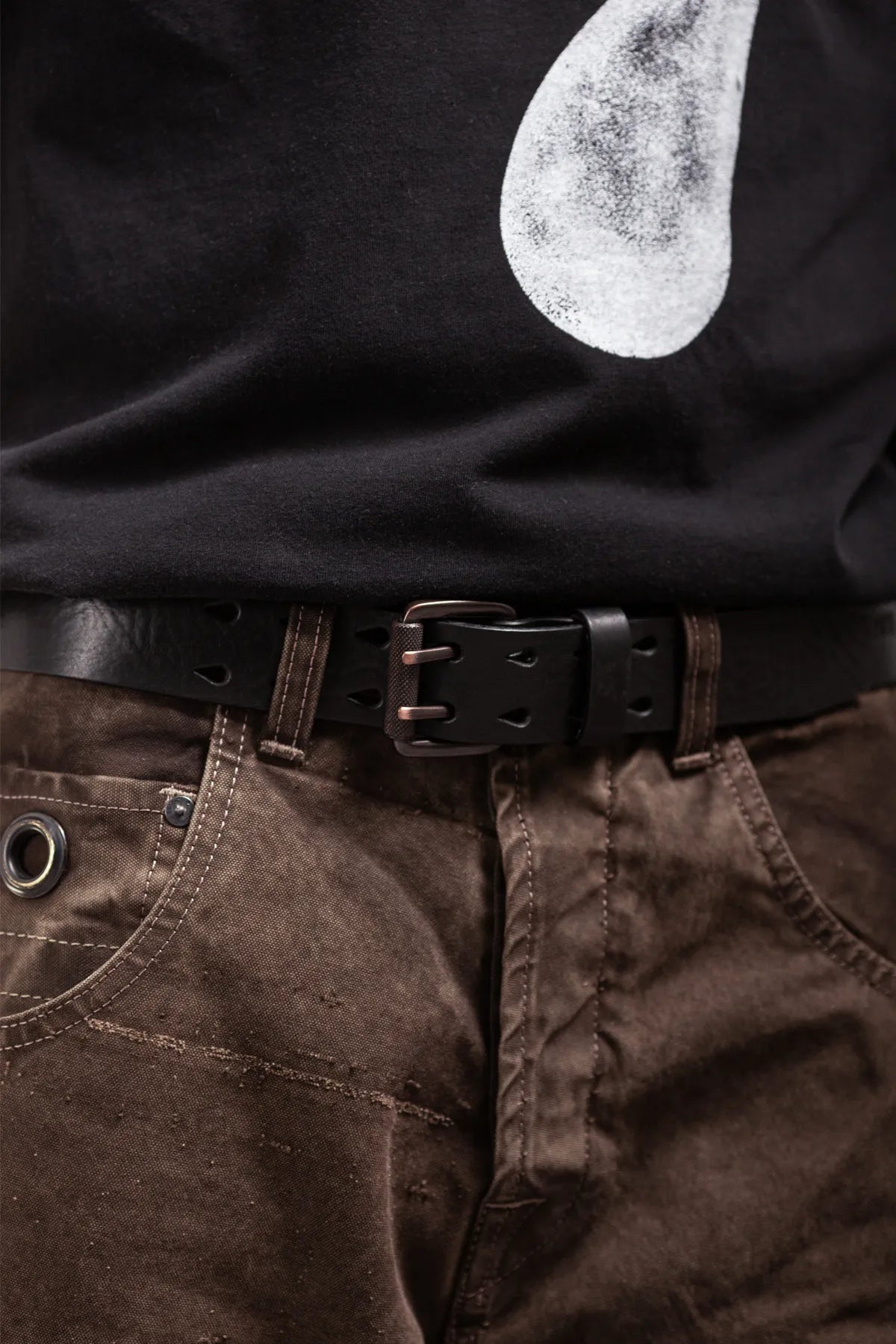 Black leather double prong belt worn with dark brown pants and black shirt