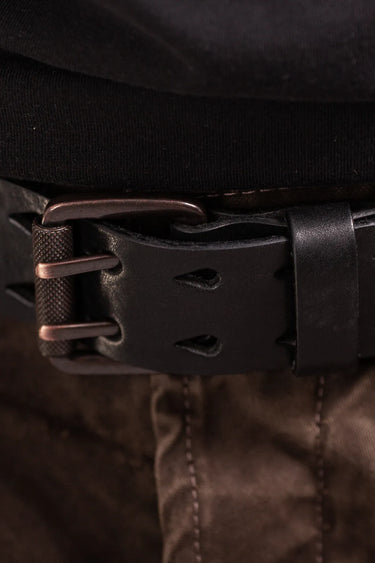 Close-up of a black leather double prong belt  with bronze toned buckle