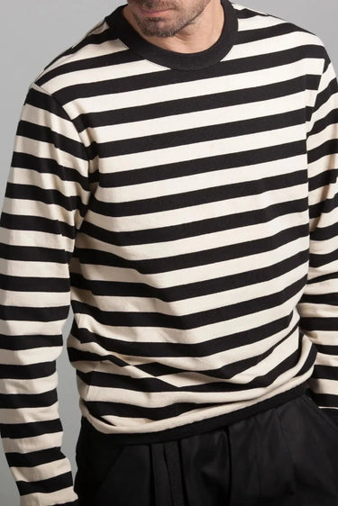 Man wearing a black and off-white striped long-sleeve shirt with black pants