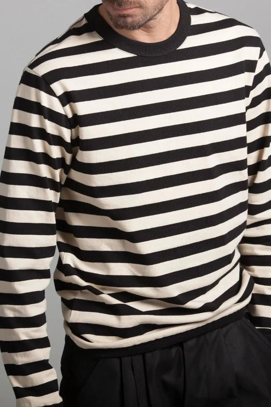 Man wearing a black and off-white striped long-sleeve shirt with black pants