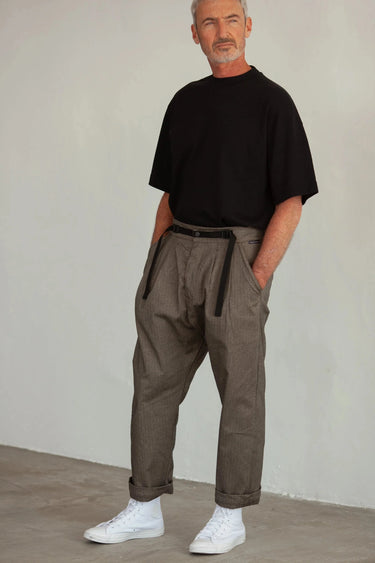 Model wearing tobacco herringbone Patton pants with a black t-shirt