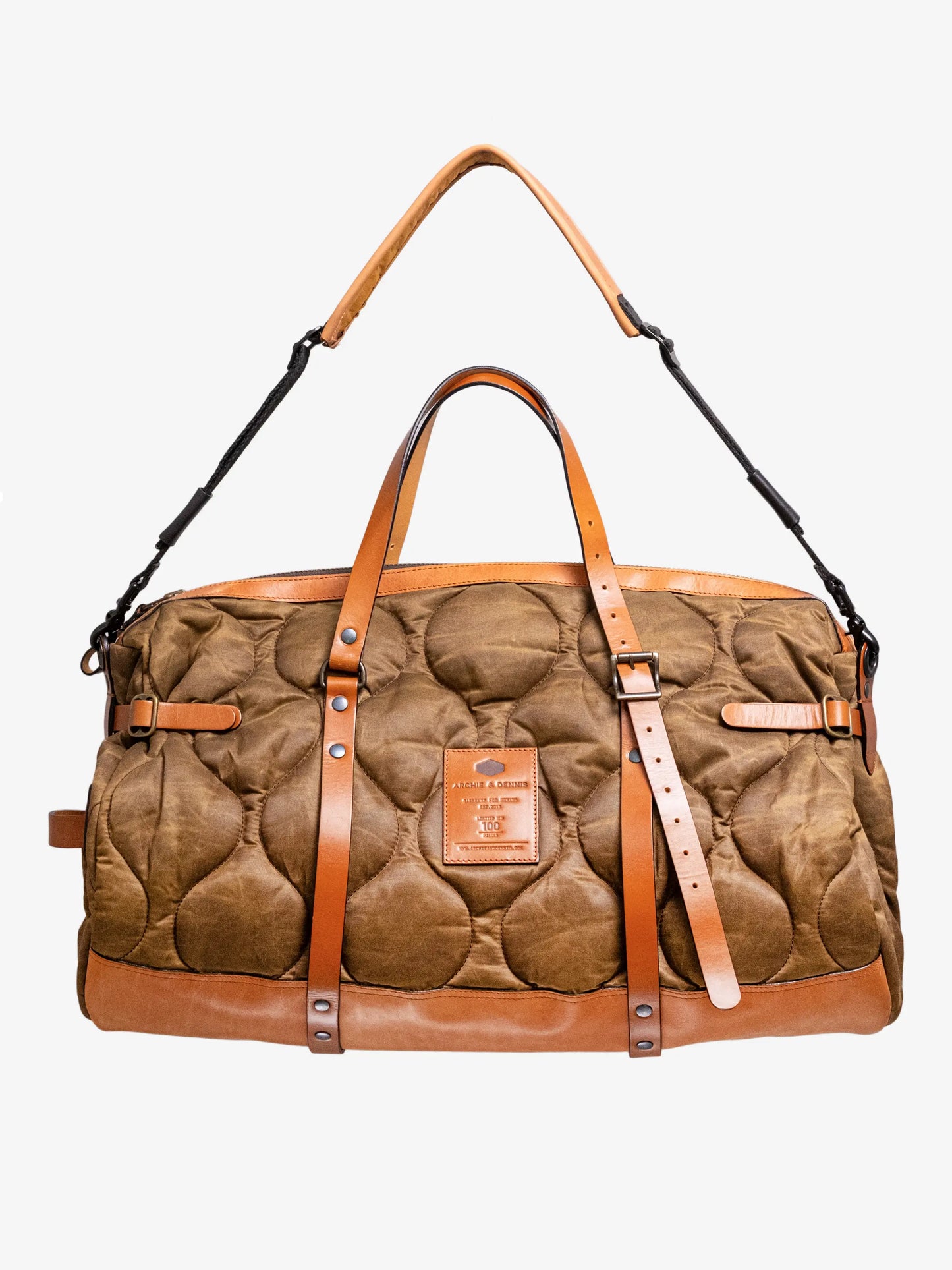 Quilted brown fabric weekender bag with tan leather straps and trim, featuring a detachable shoulder strap and a front leather patch detail.