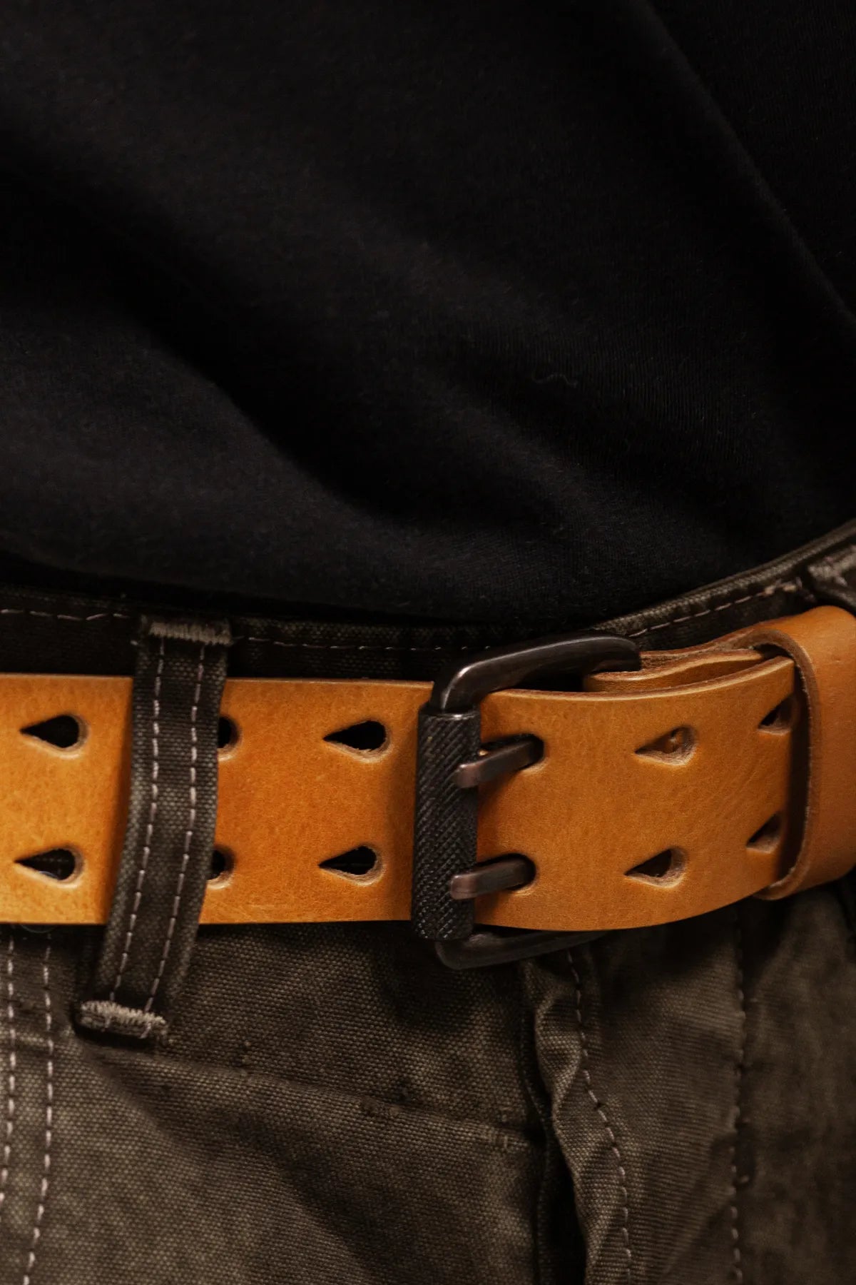 Close-up of double prong tan leather belt worn with dark pants